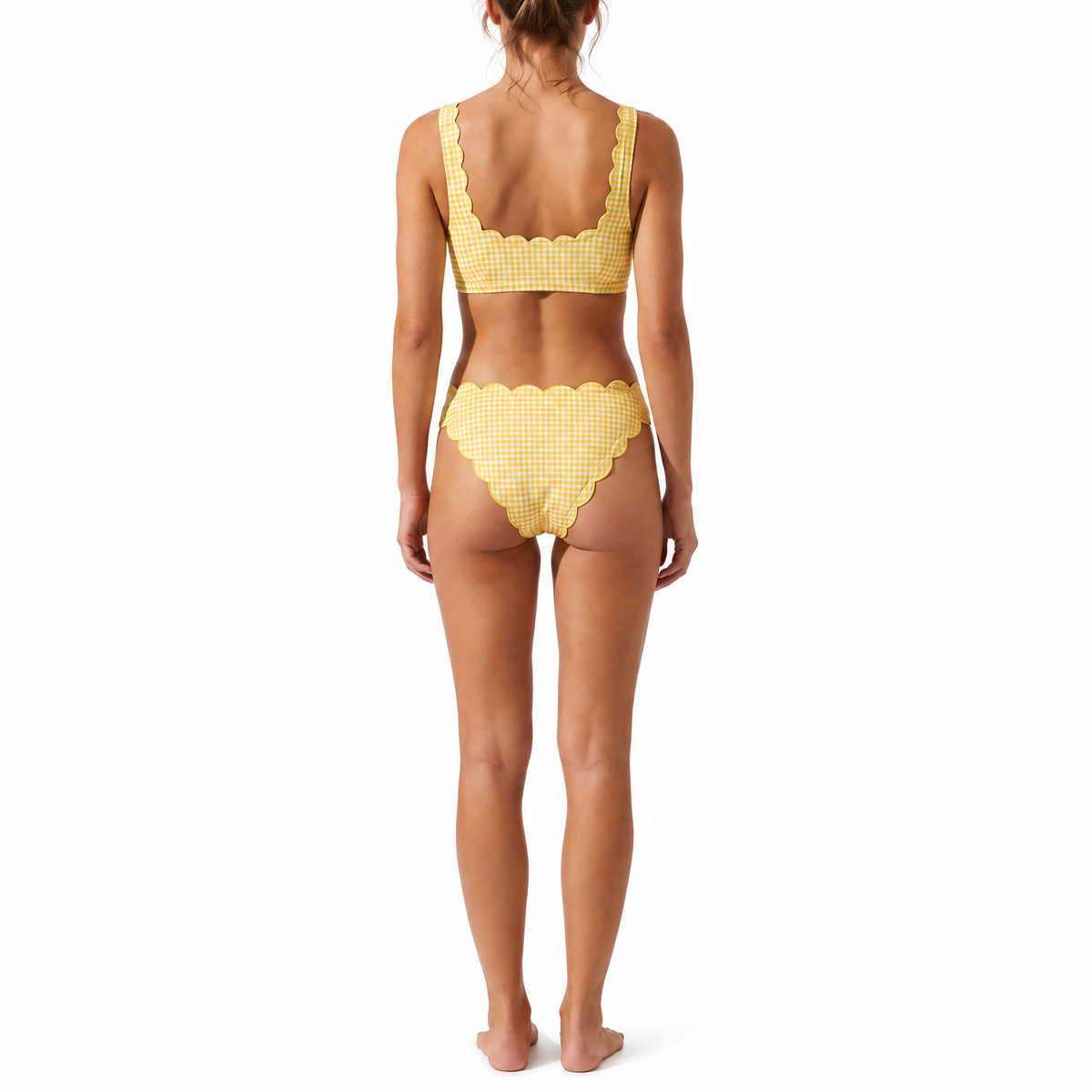 A woman modeling the back of a two-piece bikini swimsuit with a yellow and white gingham check pattern, standing against a solid white background.
