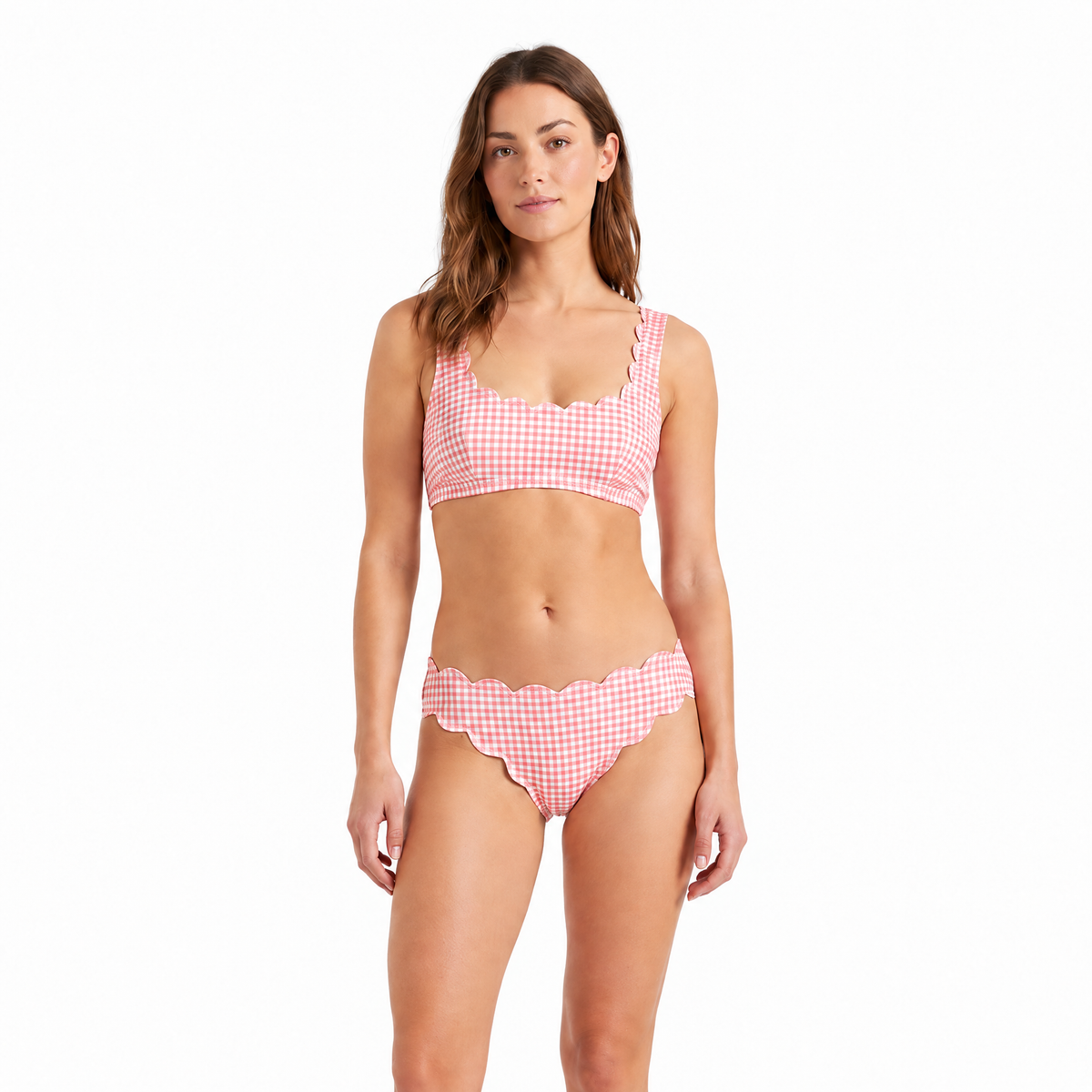 A woman modeling a two-piece bikini with a pink and white gingham check pattern and scalloped edges, set against a plain white background.